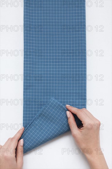 Hands of woman folding checked blue fabric