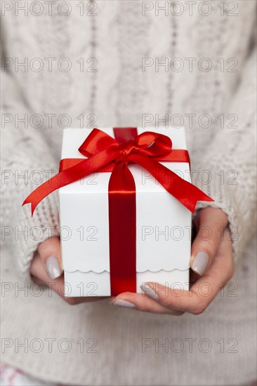 Hands of woman holding Christmas present with candy cane