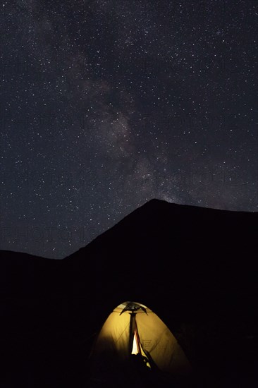 Illuminated tent by mountain at night