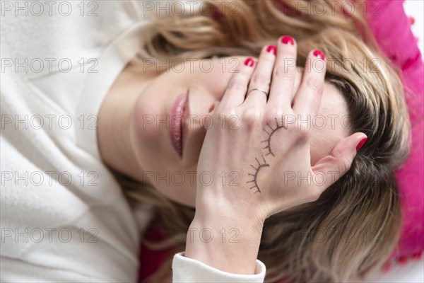 Woman with drawing of closed eyes on her hand