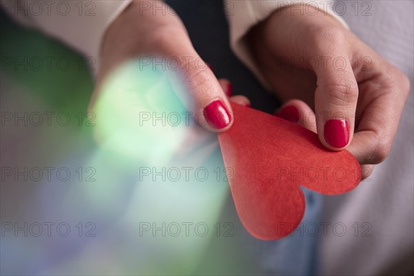 Hands of woman holding red paper heart