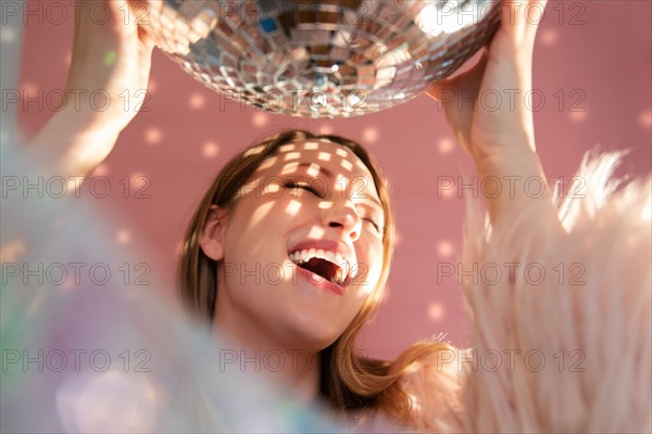 Smiling young woman holding mirror ball