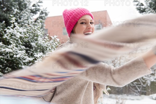 Young woman twirling with shawl in snow