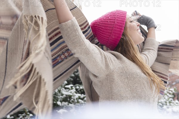 Young woman holding shawl aloft in snow