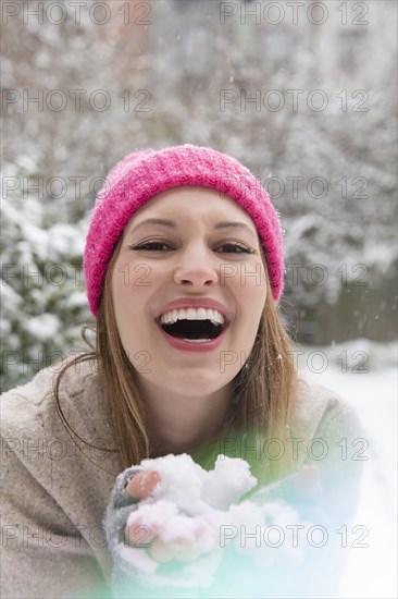 Laughing young woman holding snow
