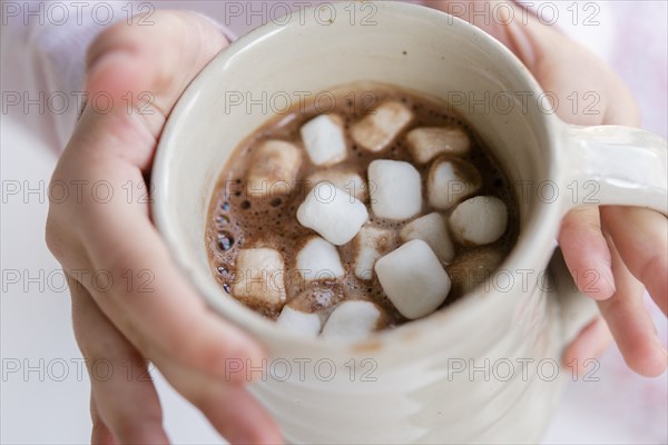 Hands of girl holding hot chocolate with marshmallows