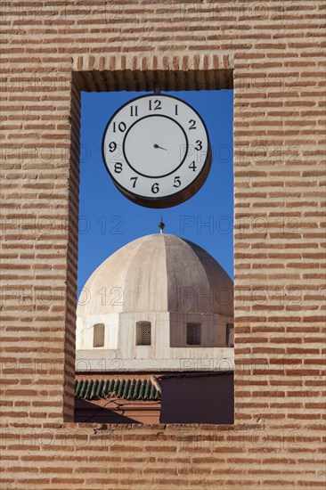 Dome behind brick window with clock in Marrakesh, Morocco