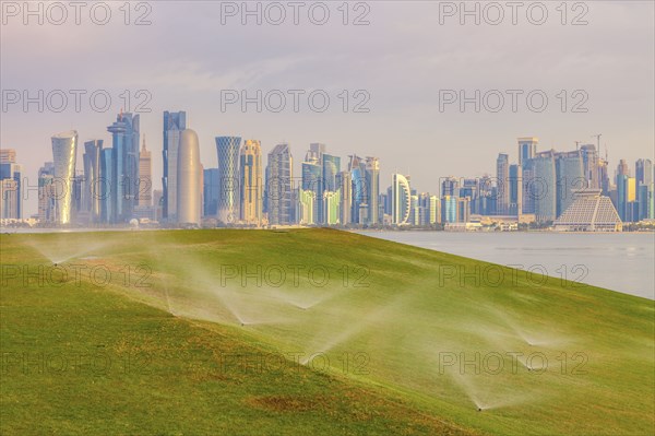 Sprinkler system on lawn by skyline of Doha, Qatar