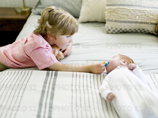 Boy holding his baby brothers pacifier