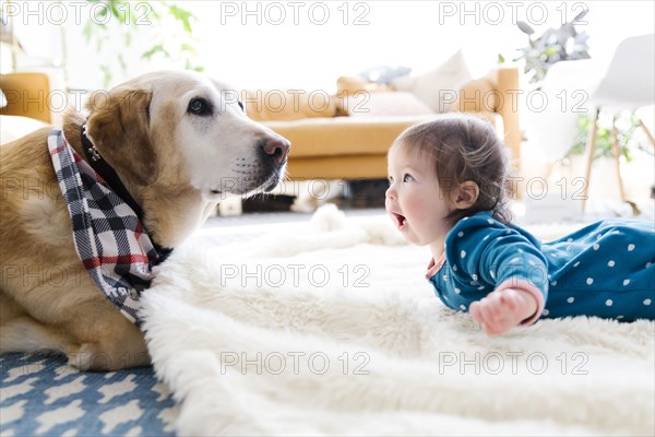 Baby girl and dog lying on rug