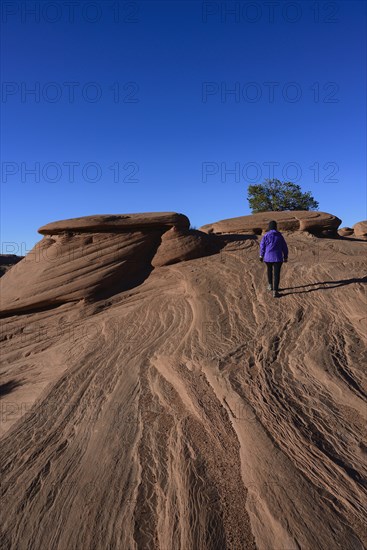 Woman walking on smooth rocks in Monument Valley, Arizona, USA