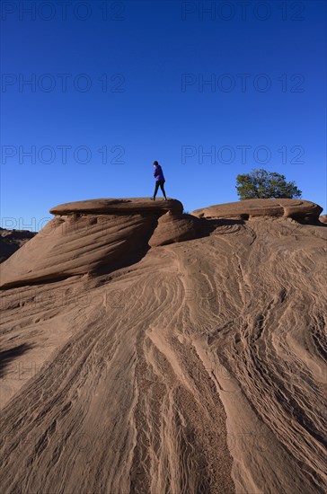 Woman walking on smooth rocks in Monument Valley, Arizona, USA