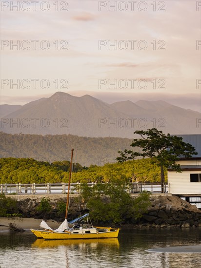 Yellow sailboat on beach at sunset in Port Douglas, Australia