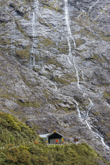 Waterfall above building in Milford Sound, New Zealand
