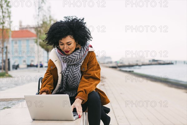 Young woman using laptop on waterfront in Lisbon, Portugal