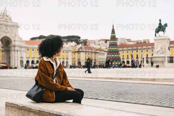 Young woman sitting in town square in Lisbon, Portugal