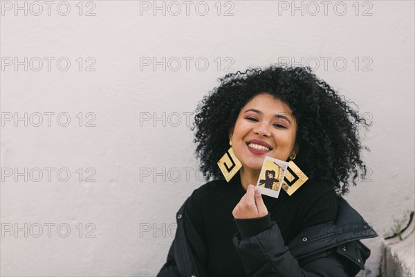 Smiling young woman holding photograph of herself