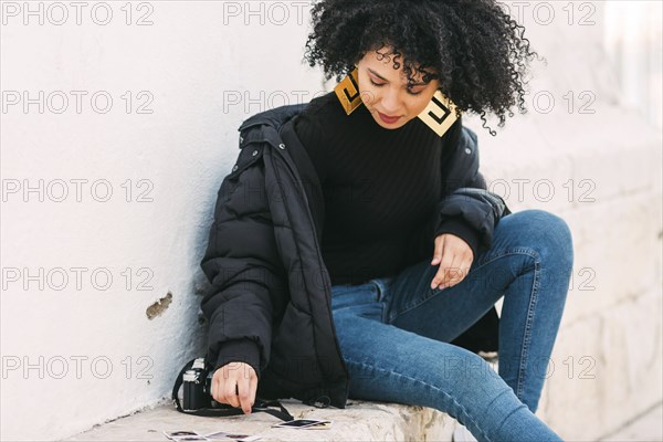 Young woman sorting photographs on bench