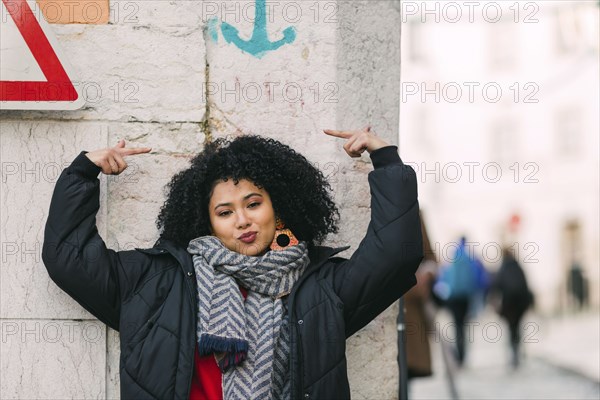 Young woman posing under arrow on wall