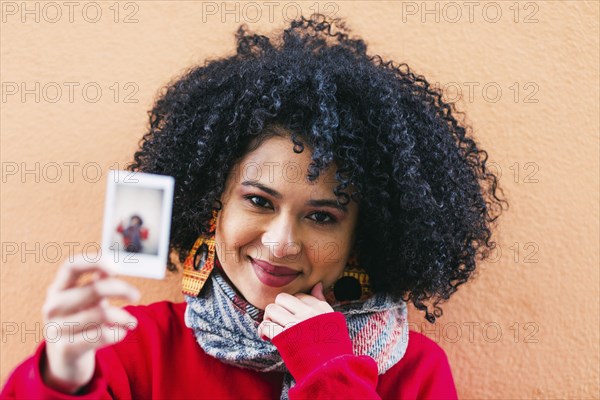 Portrait of young woman holding photograph of herself