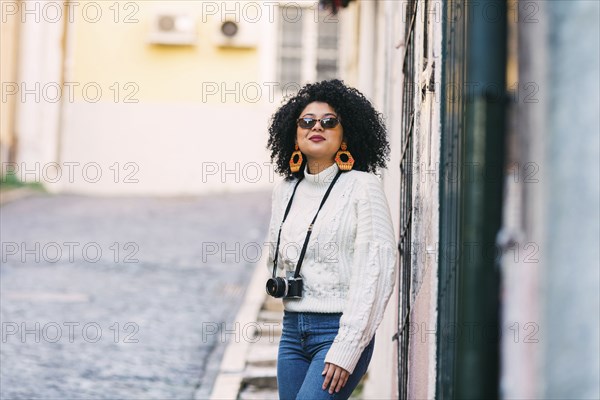 Young woman wearing sunglasses with camera on street