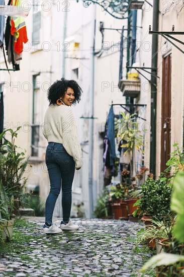 Young woman smiling over shoulder in alley