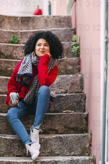 Young woman holding camera on staircase