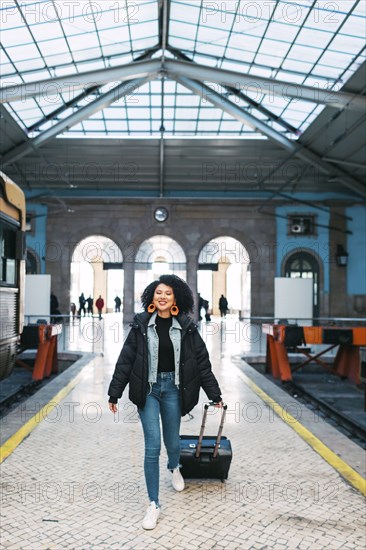 Young woman pulling suitcase in railway station