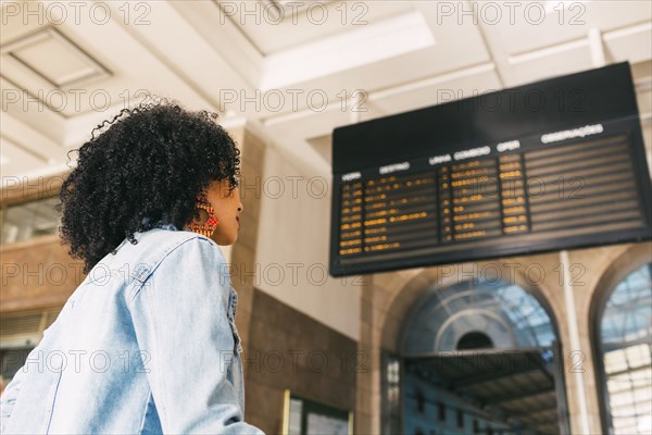 Young woman by arrival board in railway station