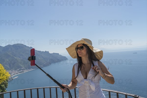 Woman using selfie stick by sea