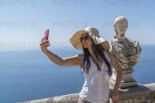 Woman taking selfie by sculpture bust