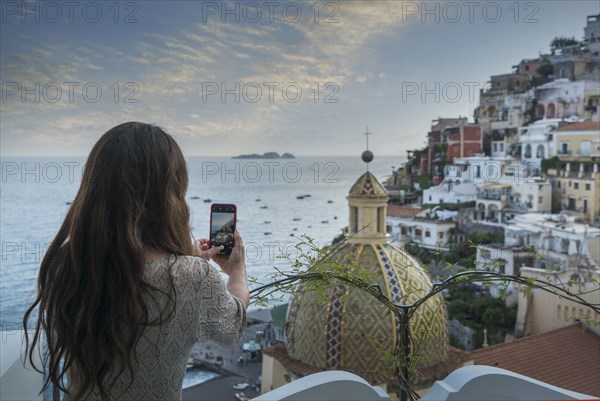 Woman taking photograph using smart phone in Positano, Italy