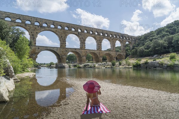 Woman wearing pink hat sunbathing by Pont du Gard in Vers-Pont-du-Gard, France