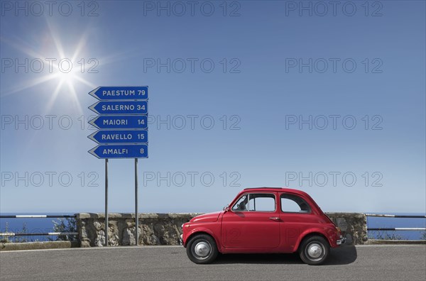 Red car by road sign on Amalfi Coast, Italy