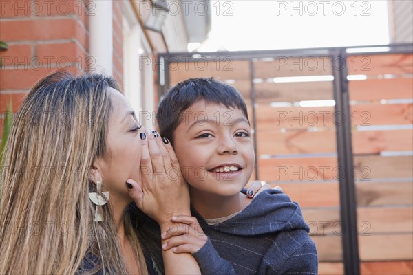 Mother whispering into her son's ear