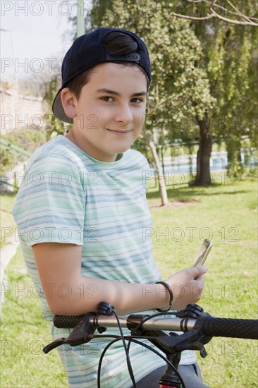 Teenage boy holding smart phone with his bicycle