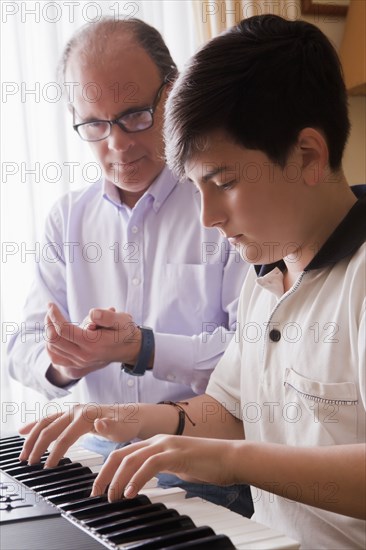 Father teaching his son piano
