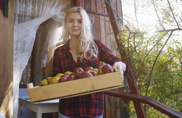 Young woman holding crate of apples