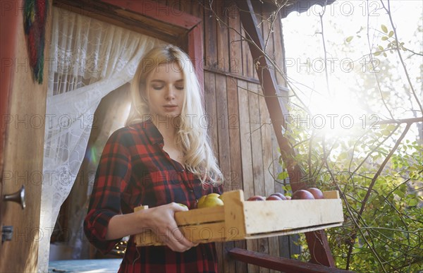 Young woman holding crate of apples