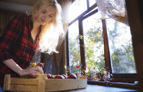 Woman with crate of apples by window