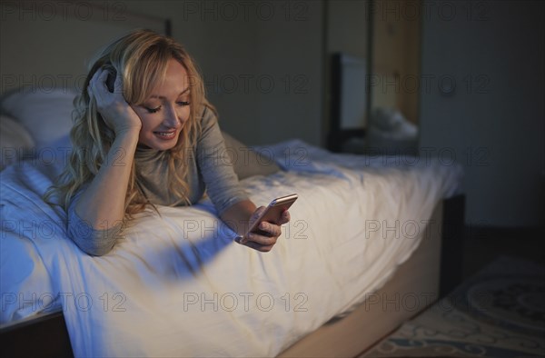 Woman using smart phone while lying on bed