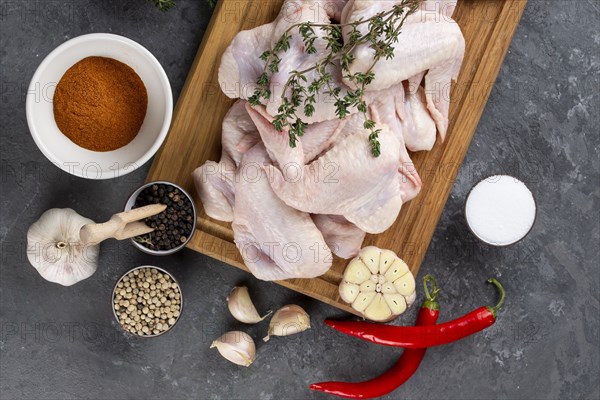 Raw chicken on cutting board with herb and spices