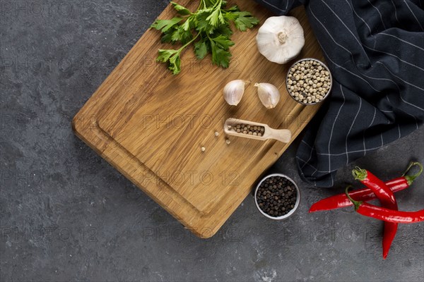 Pepper, garlic and parsley on cutting board by chili peppers