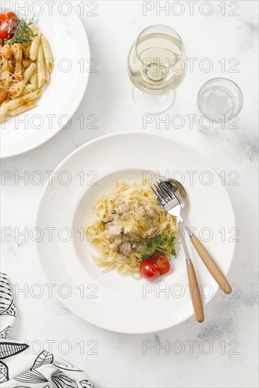 Bowl of pasta topped with cheese by white wine