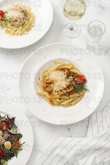 Bowl of pasta topped with cheese by white wine