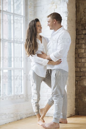 Smiling couple embracing by window