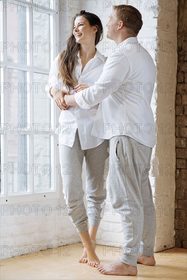 Smiling couple embracing by window