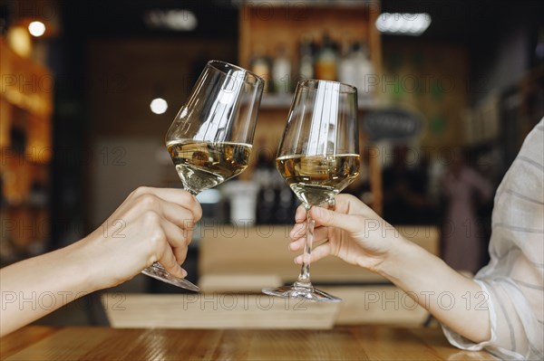 Hands of women toasting with glasses of white wine