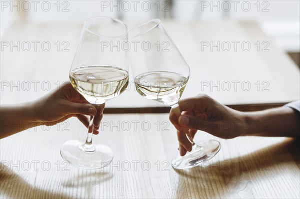 Hands of women toasting with glasses of white wine