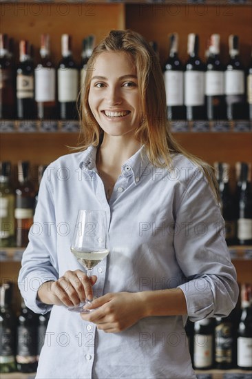 Smiling young woman holding glass of white wine